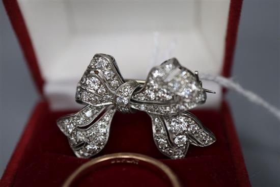 A white metal and diamond set bow brooch, 28mm, gross 5.7 grams and a 9ct and plat, three stone diamond ring